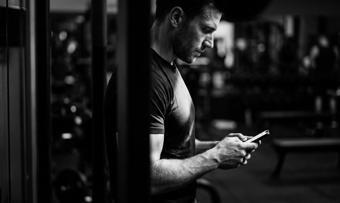 Person checking a workout app on a phone in the gym